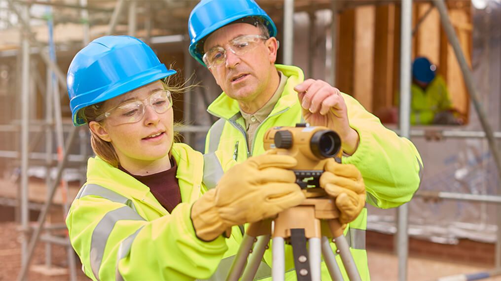 Workers wearing high visibility jackets and hard hats testing measuring equipment