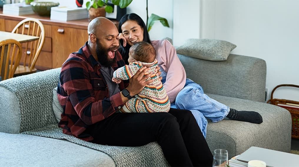 Happy couple on the sofa playing with their baby