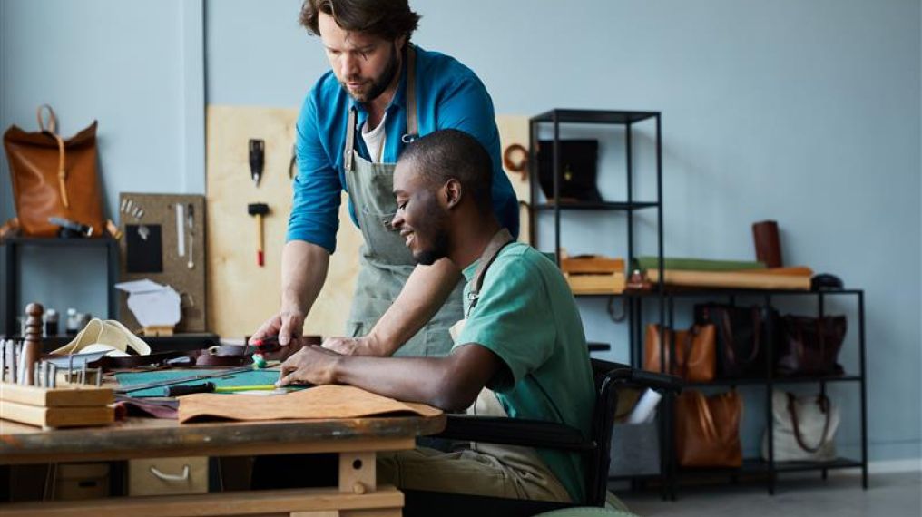 Colleagues at a workbench carrying out work, one person is in a wheelchair 